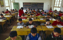 Classroom with school children reading at their desks with a teacher.