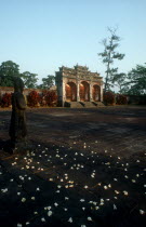 Minh Mang Tomb.  View across courtyard scattered with flowers towards ruins with large stone statues on the left.