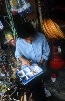 Looking down on a young woman eating from a plastic tray of different dishes in a household goods shop interior.