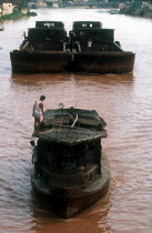 Two barges pulling a boat upriver.