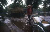 Rickshaw and truck driving through a flooded street near the Royal Hotel during Monsoon rains.