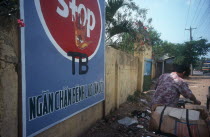 Cropped shot of a man walking with his bicycle past a poster warning about TB.