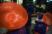 Street vendor with display of coloured plastic baskets and utensils.