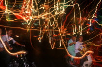 Motor cycle riders on the evening of Liberation Day and coloured light trails.