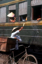 Ice cream seller with bicycle beside train.