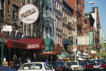 Mulberry Street in Little Italy lined with cars and restaurants.