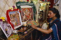 England.  Girl lighting candles at home during Dirwali.