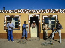 Basotho family outside typical painted home. young boys with model toy cars.