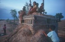 Children playing on pillbox gun shelter made of wood and packed earth.