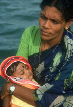 Woman holding baby in her arms. Traditionally dressed and wearing modern wrist watch