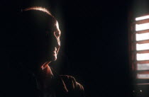 Portrait of an elderly farmer seen in a dark room with half of his face visible by light from a nearby shuttered window