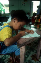 Child writing at a desk in an Agent Orange Orphanage.