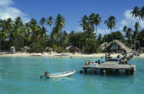 Boat jetty and beach from the sea with tourists sunbathing and swimmingBeaches Caribbean Resort Sand Sandy Seaside Shore Tobagan Tourism West Indies Holidaymakers Sunbather Travel