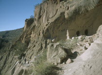 Visitors climbing ladder up a cliff towards the caves.