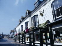 The John Harvery Brewery Shop. Black and white frontage with hanging flower baskets in Cliff High Street.