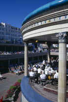 View over the Promenade Band Stand with a brass band performing on a sunny day with spectators watching from deckchairs