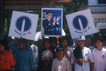 Crowd waving election campaign posters.