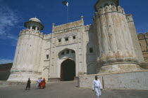 Lahore Fort.  Group of women on road walking away from Alamgiri Gate with man in foreground.