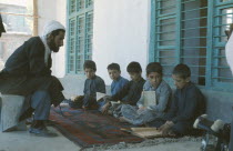 Boys seated on carpet at Koranic school being instructed in the scriptures.