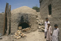 Children standing beside kiln.