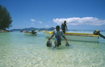 Fisherman wading ashore holding his catch.Indian Ocean