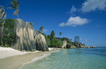 Narrow stretch of empty sandy beach with large outcrops of rock and lush vegetation.Indian Ocean