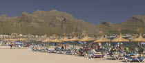 Sun loungers  tourists and parasols on the beach at Puerto de Pollensa.Mallorca