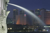 Detail of the Merlion statue at dusk with the Marina Square Complex in the background.