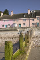 View of old fishermens cottages along the waterfront from the beach with a groyne in the foreground.