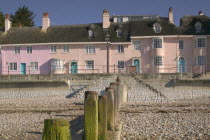 View of old fishermens cottages along the waterfront from the beach with a groyne in the foreground.