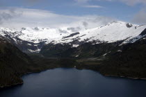 Aerial view over waters toward snow capped mountain peaks