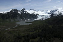 View over tree covered landscape toward waters and snow capped mountain peaks