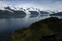 View over trees and calm waters of the bay toward snow capped mountain range