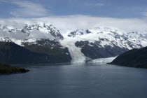 View over calm waters of the bay toward snow capped mountain range