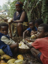 Mother and children husking cocoa pods