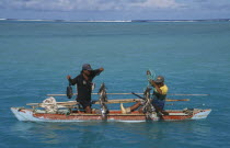 Aitutaki Lagoon.  Fishermen in wooden canoe pulling up fishing lines and catch.