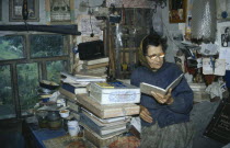 Hutsul woman writer reading from open book in domestic interior.