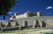 Ruined castle and fortified walls on hillside.