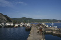 Fishing boats moored against stone jetty in lake harbour.