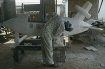 Kane Kwei brothers workshop.  Man painting and gluing together the wooden sections of a coffin in the form of an aeroplane for aircraft employee.