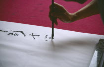 Cropped view of person writing traditional Chinese caligraphy.