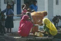 Women and children collecting water from village well and hand pump.