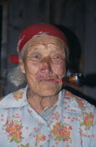 Portrait of elderly Buryat woman smoking pipe.