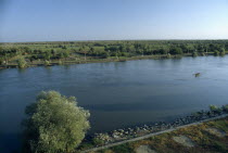 Small rowing boat on the River Danube through flat  tree covered landscape.