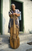 Elderly woman with a gardon  a traditional cello like instrument played by hitting the strings with a small stick.