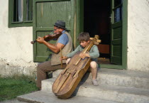 Man and child playing violin and a gardon  a cello like instrument played by hitting the strings with a small stick.