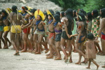 Group of Xikrin Indians wearing feather head dresses and bead jewellery and with their feet and faces painted with red urucu juice. Brasil Kaiapo