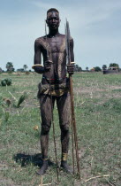 Portrait of Dinka warrior carrying spears with his body painted with a mixture of dung and ash and wearing traditional jewellery.