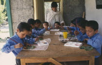 Female teacher at boys school with pupils in art class.