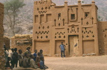 Dogon village Elders house with man standing outside and group of children in the foreground.